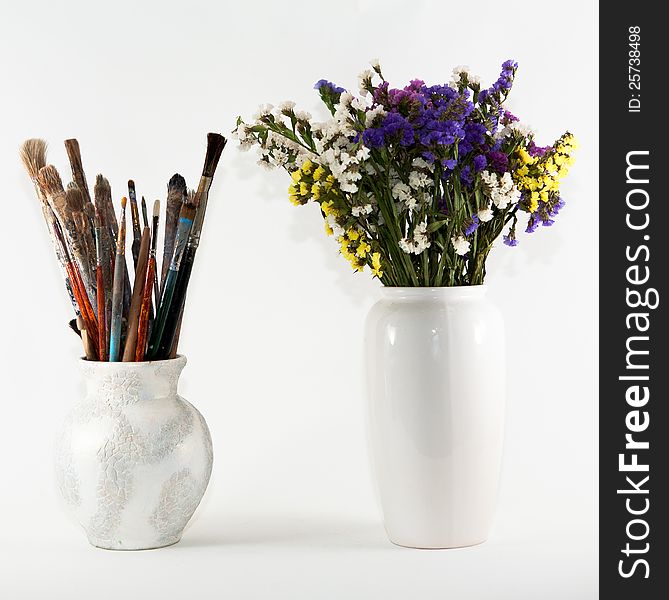 Jug with paint brushes and vase with wild flowers. Jug with paint brushes and vase with wild flowers