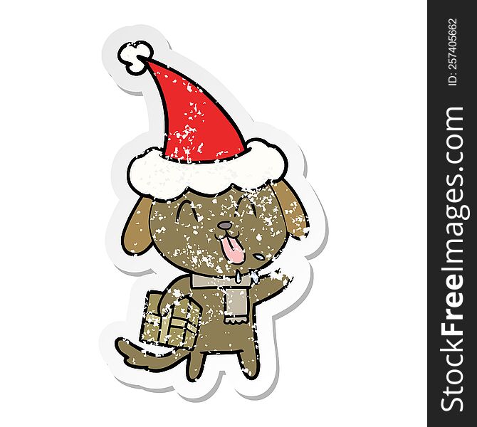 Cute Distressed Sticker Cartoon Of A Dog With Christmas Present Wearing Santa Hat