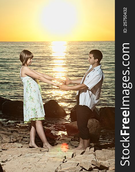 Young couple staying on stones near the lake at sunset. Young couple staying on stones near the lake at sunset