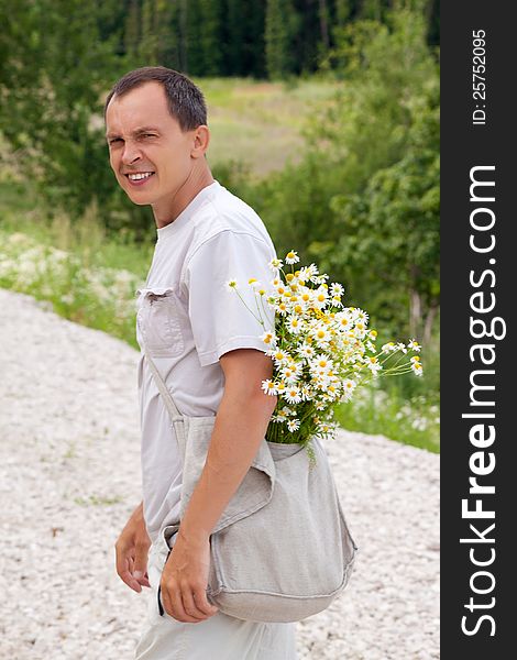 The young man with camomiles in a bag looks back
