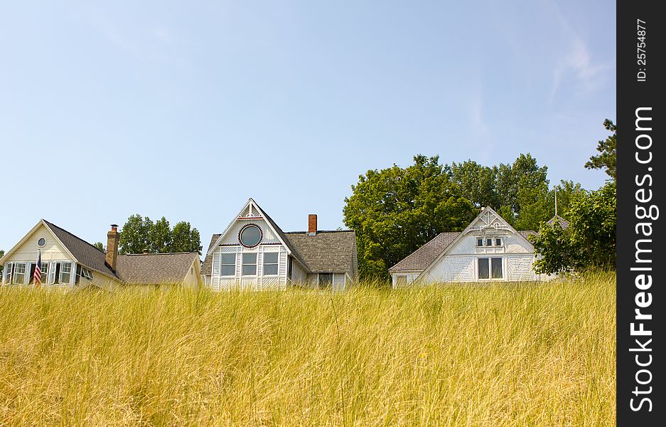 A row of beach houses near beach grass in the summer time.
