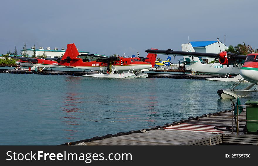 Pontoon planes or floatplanes moored in the sea alongside a jetty eqipped with pontoons to land on water. Pontoon planes or floatplanes moored in the sea alongside a jetty eqipped with pontoons to land on water