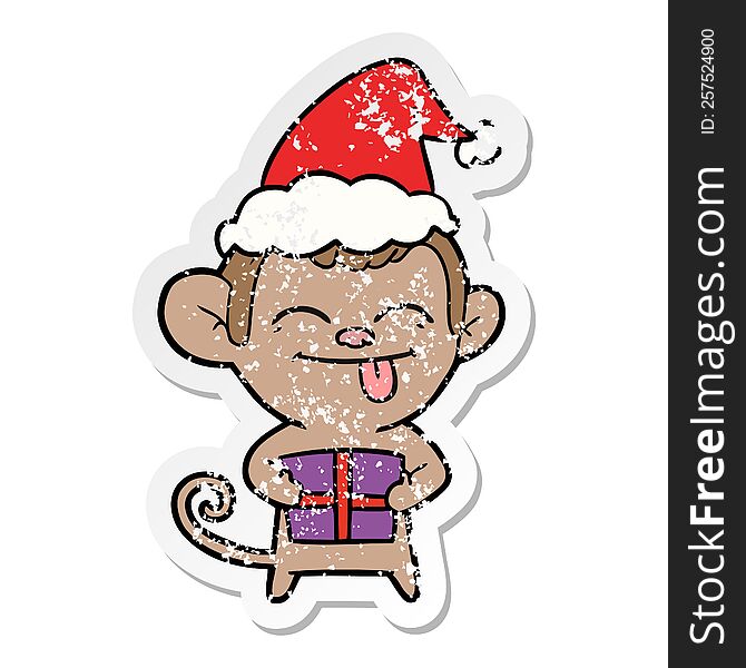 funny hand drawn distressed sticker cartoon of a monkey with christmas present wearing santa hat