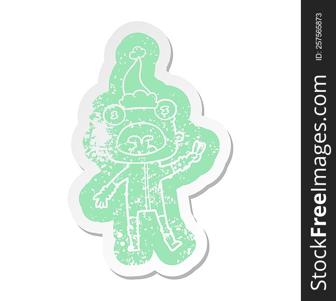 Cartoon Distressed Sticker Of A Weird Alien Waving Wearing Santa Hat