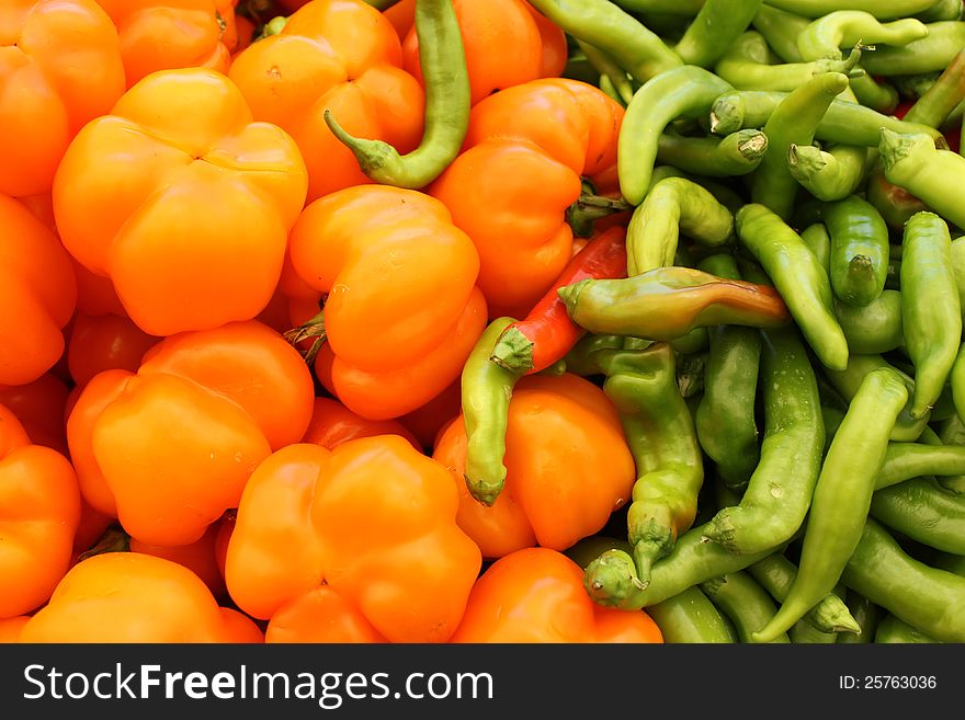 Sweet yellow peppers and green chili peppers as an agricultural background. Sweet yellow peppers and green chili peppers as an agricultural background