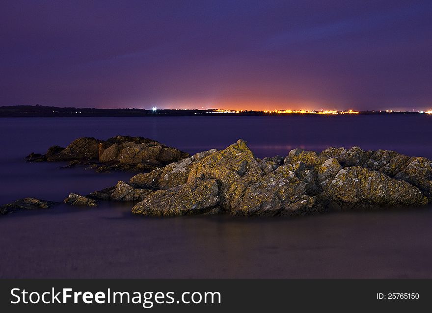 Seaside. Coast at night in Skerries, Ireland. Rocks in water. long exposure.