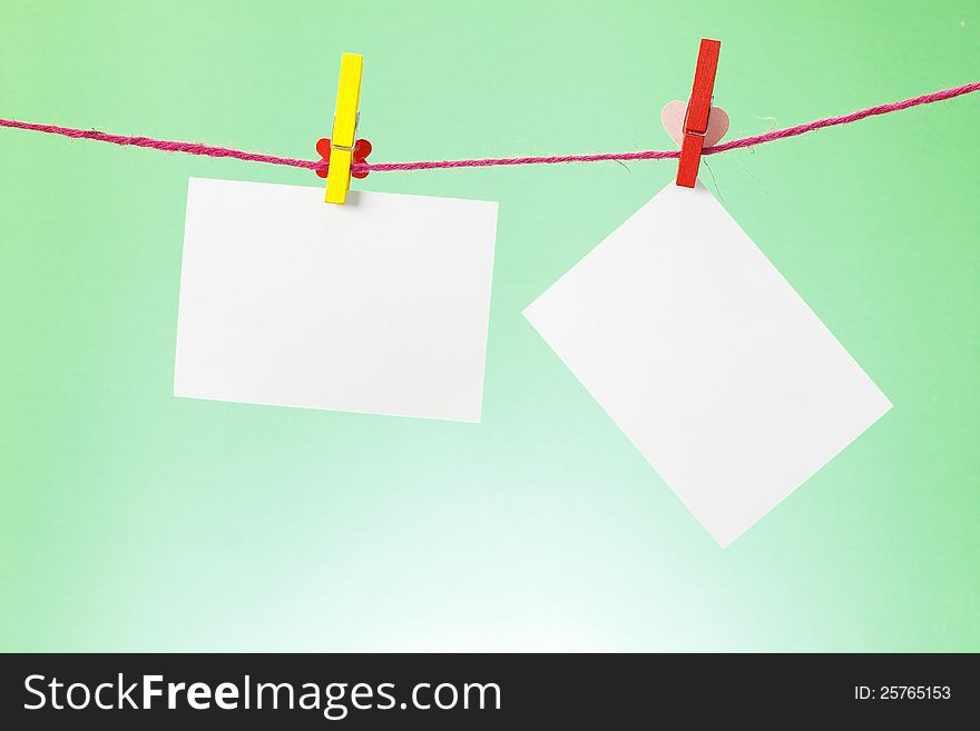 Photo paper hanging on the clothesline on light green background