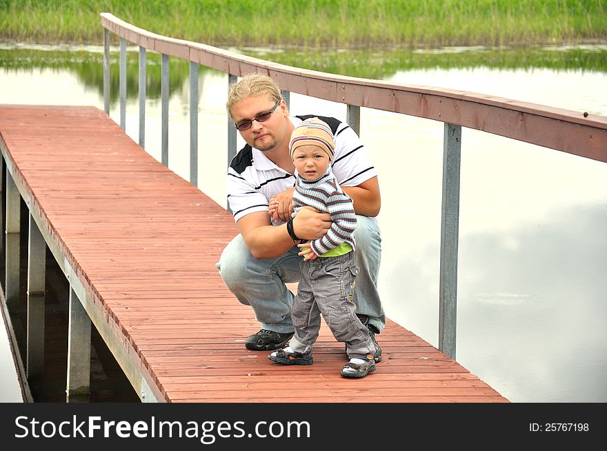 Father and son  on  a wooden pier near a river