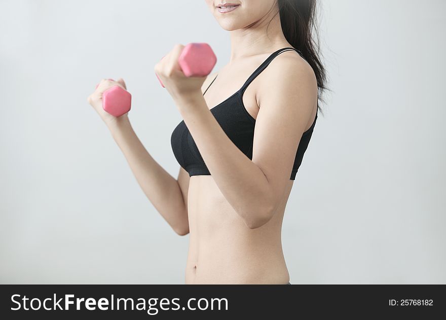 The girl with a sports figure does exercises with dumbbells. The girl with a sports figure does exercises with dumbbells