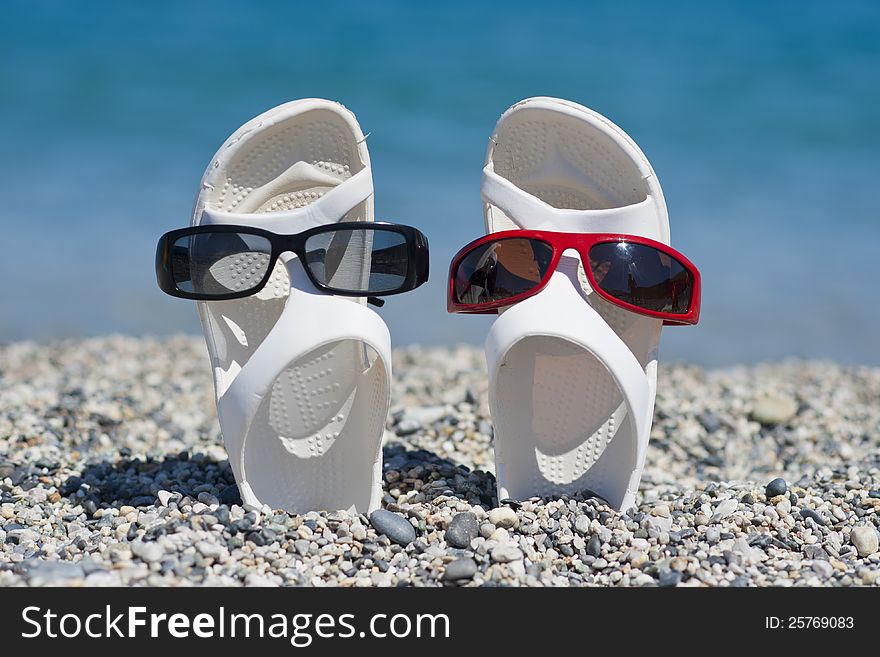Two white sandals dressed with different sunglasses. Two white sandals dressed with different sunglasses