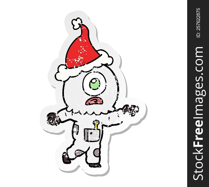 hand drawn distressed sticker cartoon of a cyclops alien spaceman pointing wearing santa hat