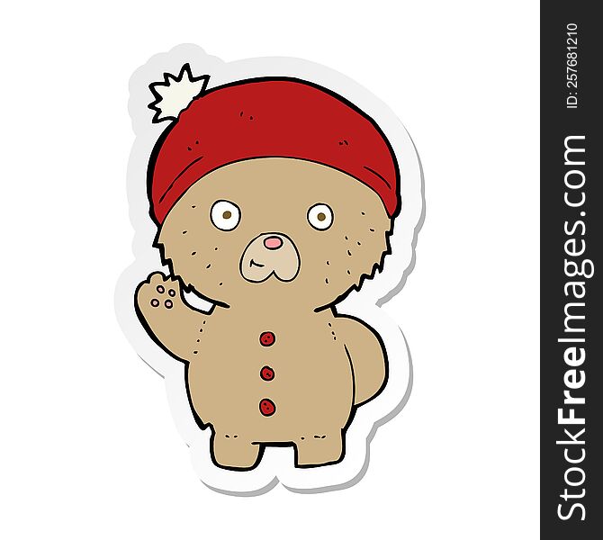 sticker of a cartoon waving teddy bear in winter hat