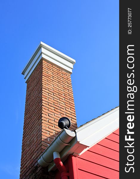 Orange brick pipe and black roof on blue sky