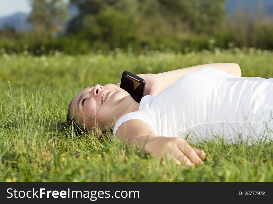 Smiling cute girl talking on mobile tablet phone, outdoors on sunny summer afternoon. Smiling cute girl talking on mobile tablet phone, outdoors on sunny summer afternoon