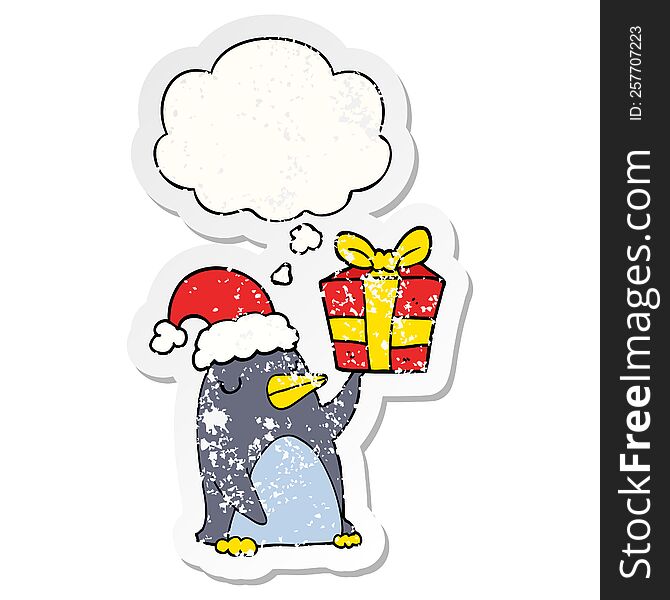 cartoon penguin with christmas present with thought bubble as a distressed worn sticker