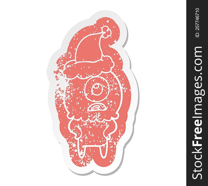 Cartoon Distressed Sticker Of A Cyclops Alien Spaceman Wearing Santa Hat