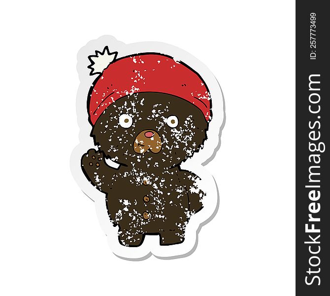 retro distressed sticker of a cartoon waving black teddy bear in winter hat