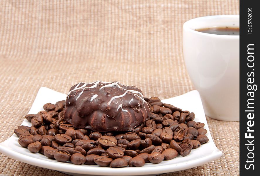 Chocolate pastry lies on coffee bob on a background a cup