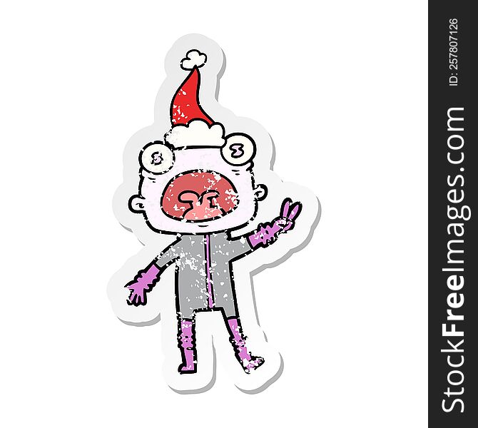 hand drawn distressed sticker cartoon of a weird alien waving wearing santa hat