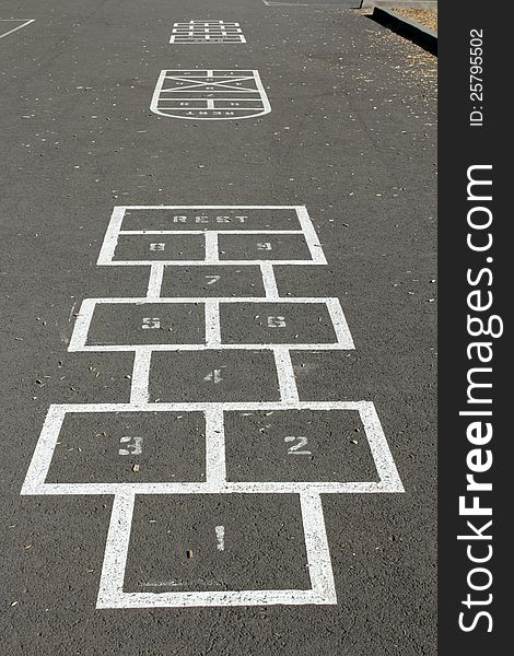 A few hopscotch game courses are outlined on the pavement of a children's playground on a sunny morning. A few hopscotch game courses are outlined on the pavement of a children's playground on a sunny morning.