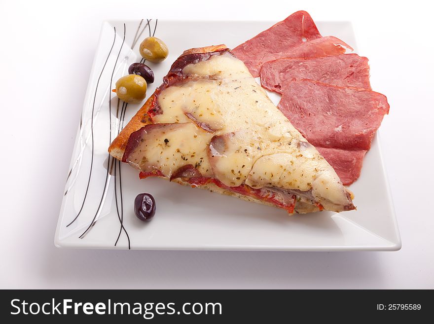 Pizza slice with olive and salami on a plate on white