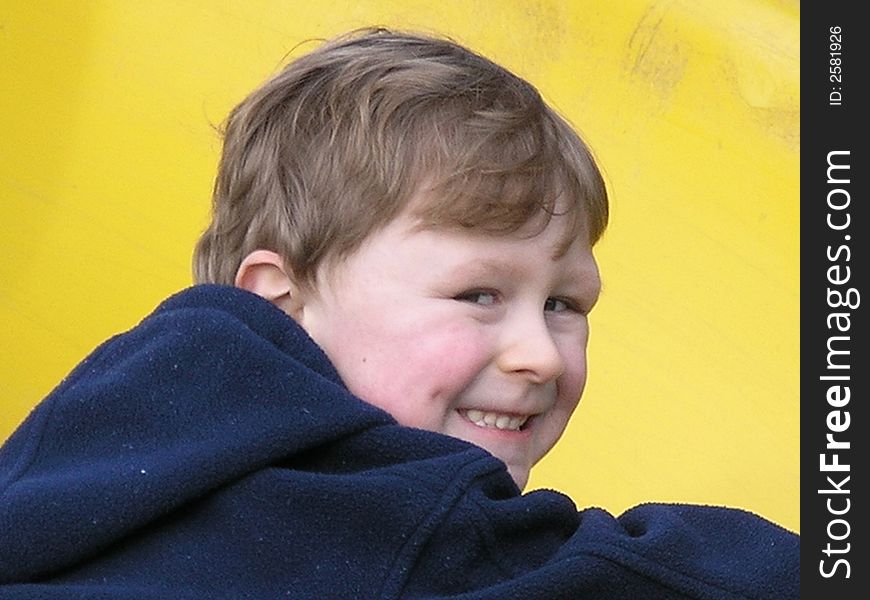 Smiling boy in front of yellow background in blue jacket. Smiling boy in front of yellow background in blue jacket