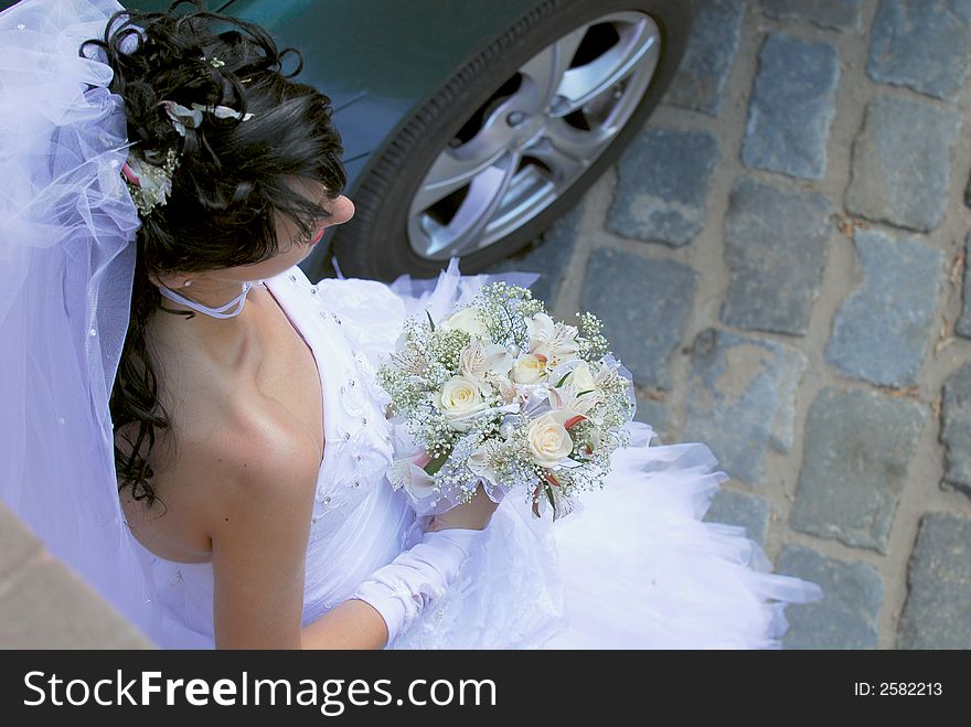 The bride stands on wedding with a bouquet of roses