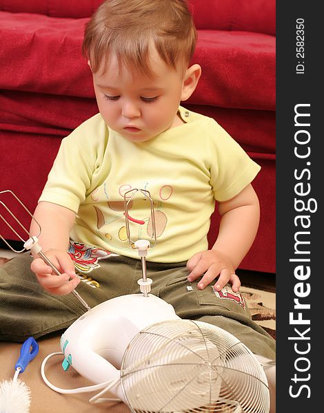 Little blond baby boy playing with mixer