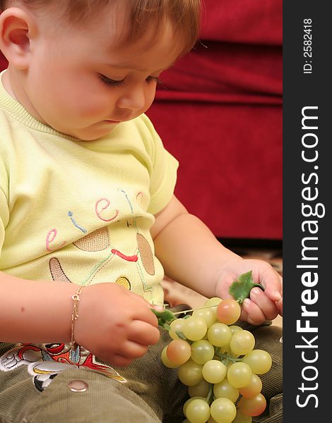 Expressive blond baby boy amazed with grapes in hand. Expressive blond baby boy amazed with grapes in hand
