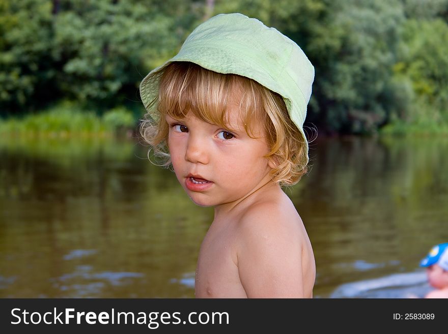 Little kid stands near river