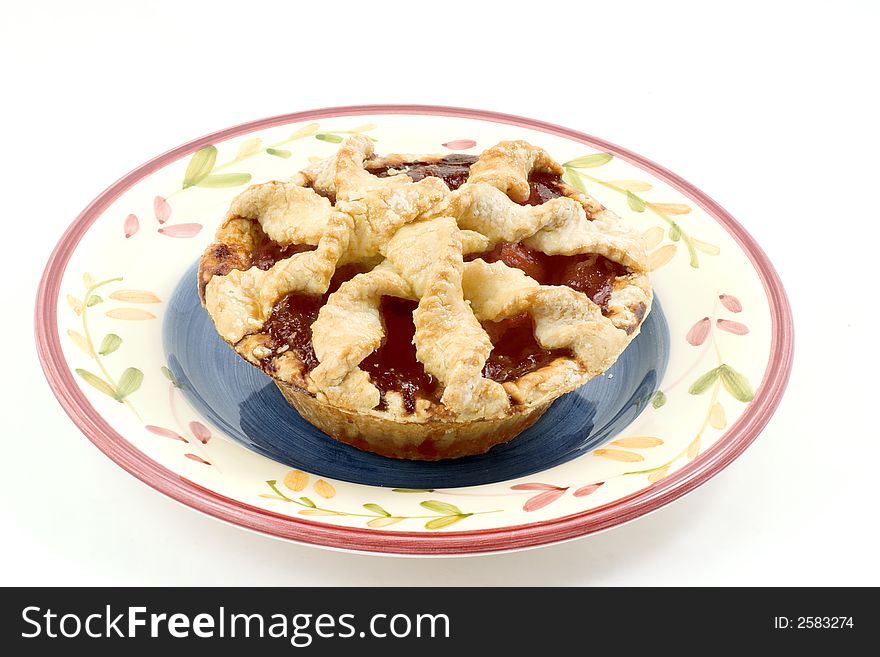An individual cherry peach pie with lattice crust on an interesting plate.