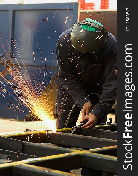 Steel worker using an acetylene torch to cut steel tubing. Steel worker using an acetylene torch to cut steel tubing