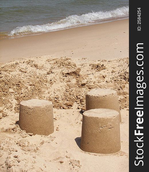 Three molded piles of wet sand on the beach. Three molded piles of wet sand on the beach