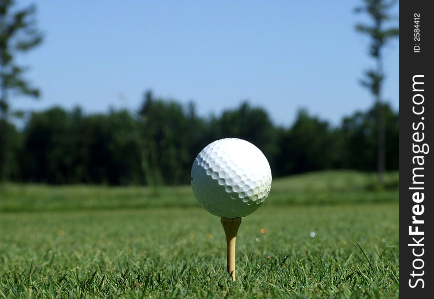 A golf ball on a tee on a course. A golf ball on a tee on a course