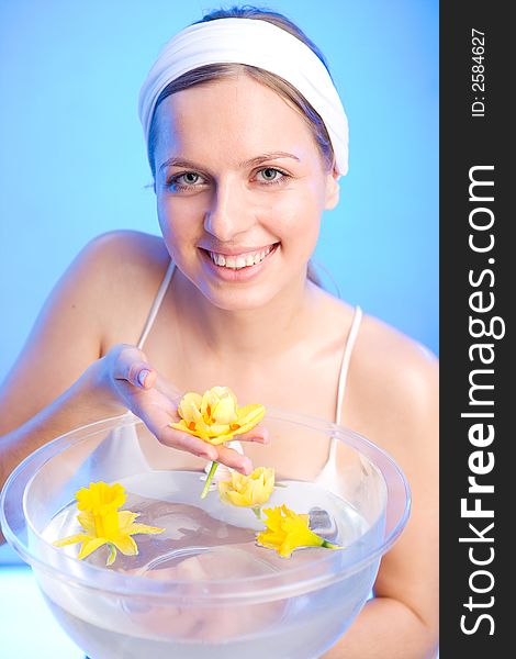 Beautiful young woman is holding one of the flowers that are in a bowl of water. Beautiful young woman is holding one of the flowers that are in a bowl of water