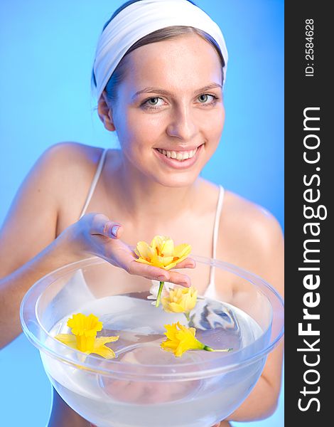 Beautiful young woman is holding one of the flowers that are in a bowl of water. Beautiful young woman is holding one of the flowers that are in a bowl of water