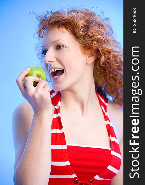 Beautiful redhaired girl is biting off a green apple. Beautiful redhaired girl is biting off a green apple