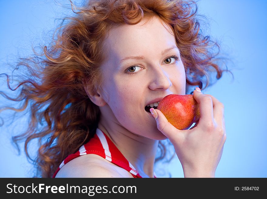 Beautiful redhaired girl is biting off an apple. Beautiful redhaired girl is biting off an apple