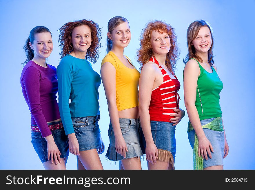 Five happy young girlfriends wearng colourful shirts and miniskirts are standing in a row. Five happy young girlfriends wearng colourful shirts and miniskirts are standing in a row
