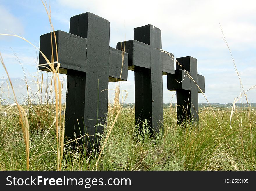 Three black crosses in a grass on a background of the sky