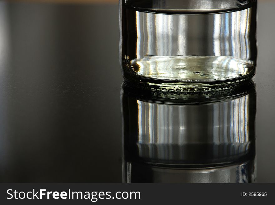 Reflected glass jar of liquid.