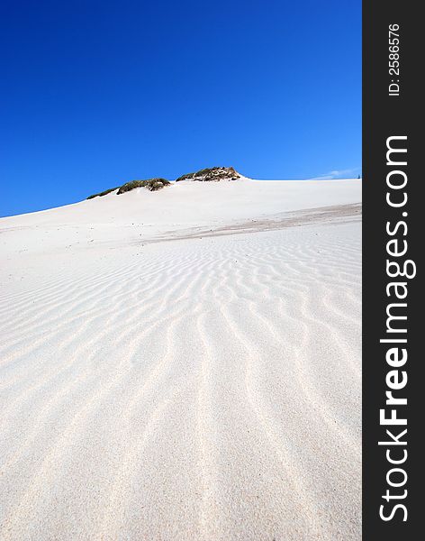 sand dunes on white desert with green hill on the blue sky background. sand dunes on white desert with green hill on the blue sky background