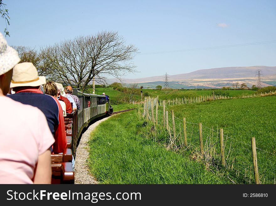 Narrow gauge passenger train filled with tourists travelling through the countryside