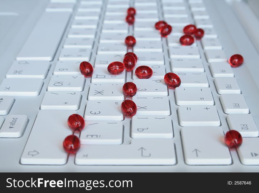 Red capsules on the white keyboard. Red capsules on the white keyboard