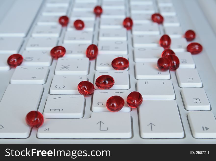 Red capsules on the white keyboard. Red capsules on the white keyboard