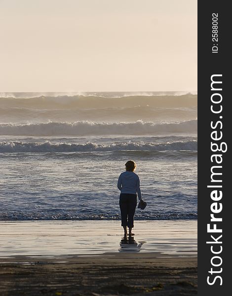 Woman standing barefoot on an ocean beach. Woman standing barefoot on an ocean beach