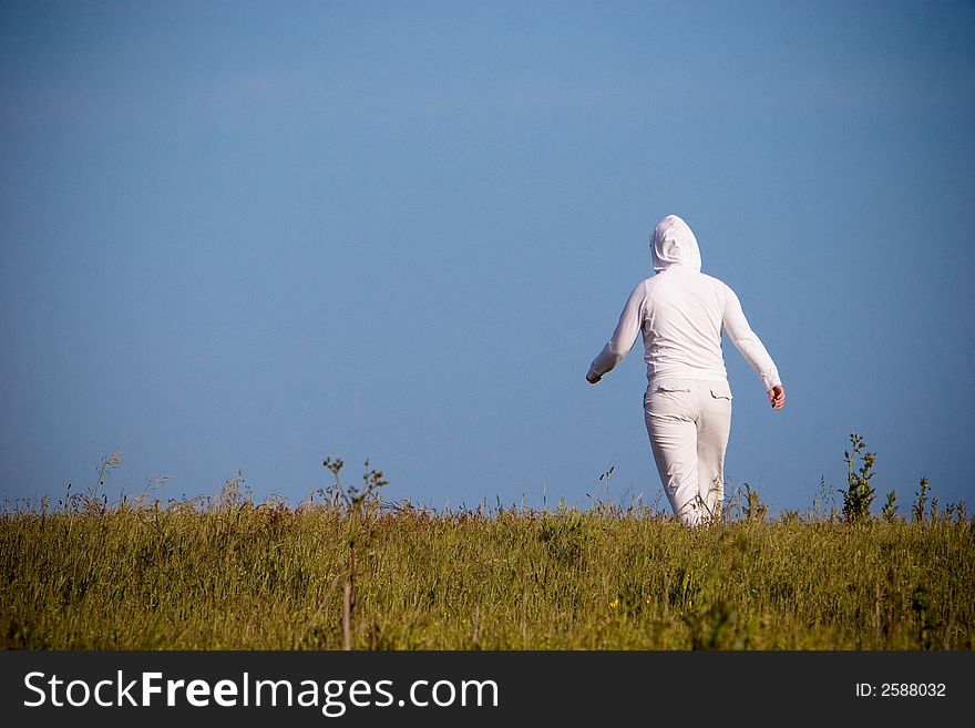 Individual woman walking away through a field.