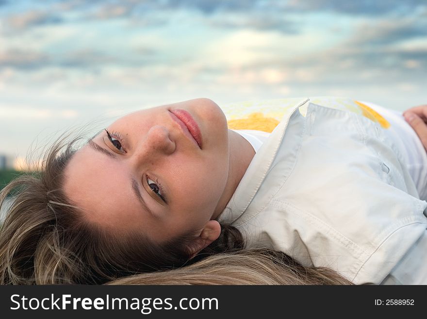 Girl in white lays under the sunset cloudy sky. Girl in white lays under the sunset cloudy sky