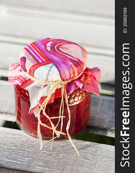 Strawberry jam in a glass on wood