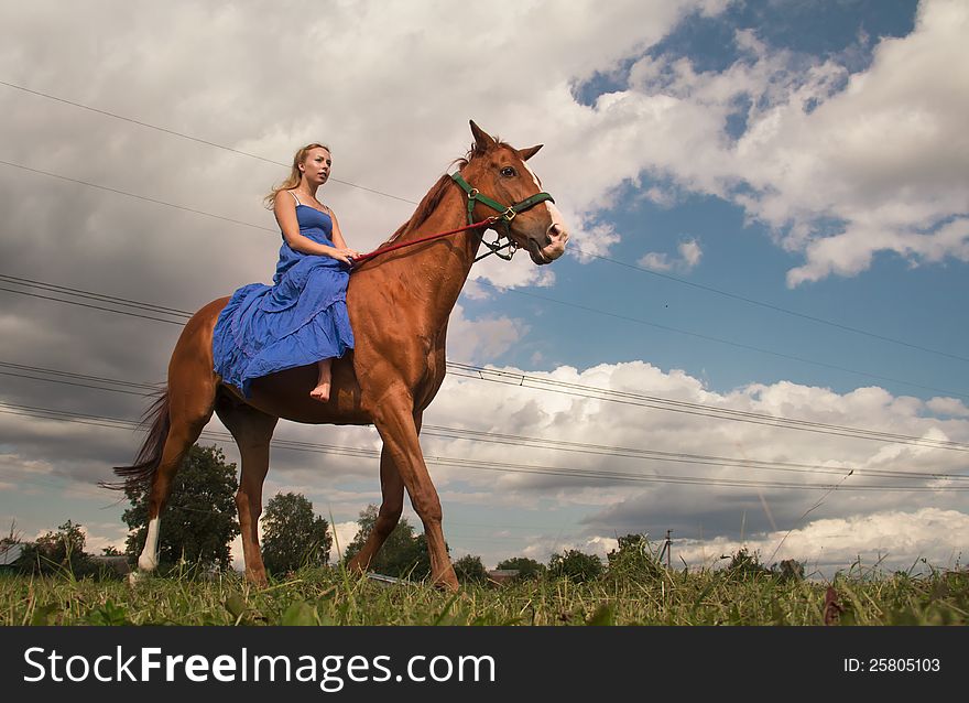 Young woman in blue dress on horseback. Young woman in blue dress on horseback